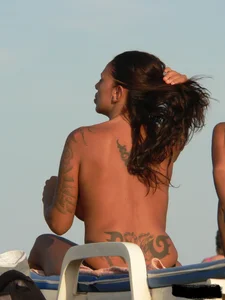 Topless tattooed lady on the beach with fake big tits