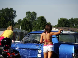 Group of cute girls at a car wash in bikinis and shorts