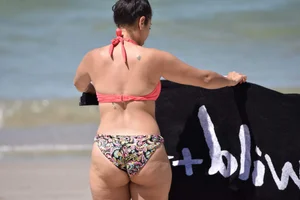 Huge boobed thick brunette babe on the beach in a bikini