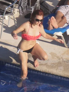 Sexy red haired girl in pink and black bikini at the pool