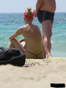 Topless skinny blonde lady in a g-string bikini at the beach