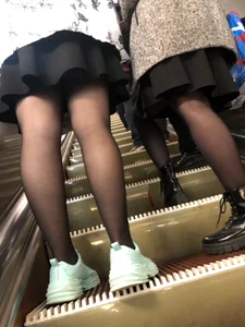 Two candid girls in skirts and black pantyhose on a subway escalator low angle creepshot