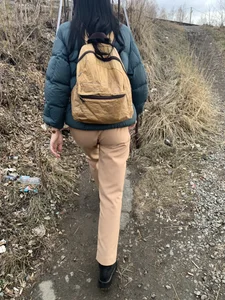 Candid girl wearing pants and a backpack walking down a suburban road
