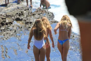 Blonde in blue thong swimsuit on the beach with friends