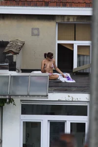Neighbor on rooftop tanning in bikinis