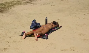 Sexy girl getting some sun laying on the beach in thong bikini