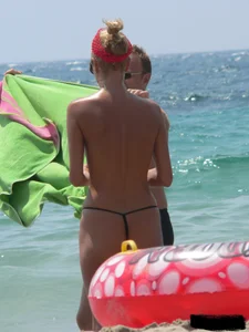 Topless skinny blonde lady in a g-string bikini at the beach