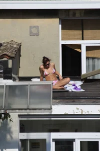 Neighbor on rooftop tanning in bikinis