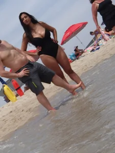 Thick brunette with huge boobs on the beach in black swimsuit