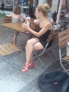 Girl in sandals with hot legs sitting in a street cafe