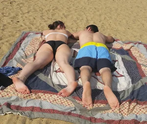 Sexy girl on the beach laying out and bending over in her bikini