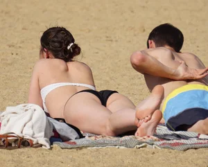 Sexy girl on the beach laying out and bending over in her bikini