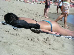 Brunette looking sexy on the beach in a blue thong bikini