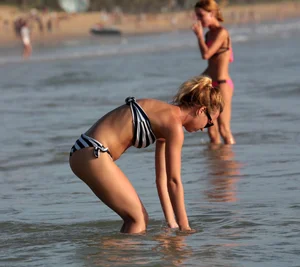 Skinny sexy blonde in little striped bikini in the water