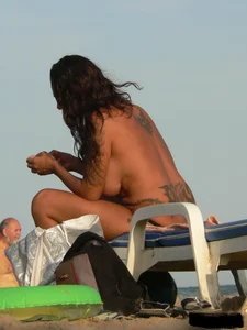 Topless tattooed lady on the beach with fake big tits