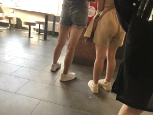 Couple of candid teens in shorts making order in fast food restaurand creepshots