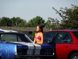 Group of cute girls at a car wash in bikinis and shorts