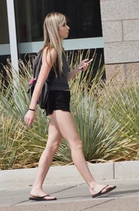 Adorable Girl in Mini Shorts and Slippers Walking Down the Street