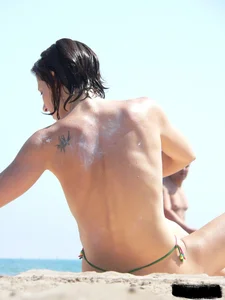 Topless beach milf looking sexy in a tiny g-string bikini