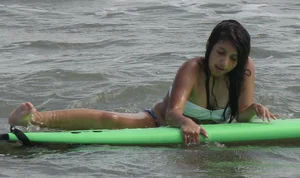 Brunette bikini girl on the beach and surfing in her bikini