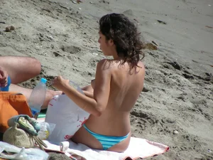 Topless brunette babe on the beach with an incredible bubble butt