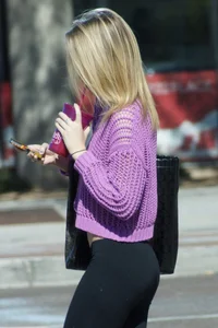 Beautiful skinny blonde in tight leggings and purple crop top showing sexy stomach