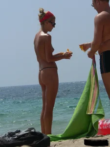 Topless skinny blonde lady in a g-string bikini at the beach