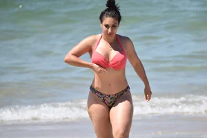 Huge boobed thick brunette babe on the beach in a bikini