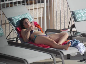 Sexy ass brunette sunbathing by the pool in thong bikini