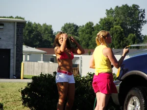 Group of cute girls at a car wash in bikinis and shorts