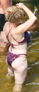 Chunky blonde enjoying some drinks in the water in her purple bikini