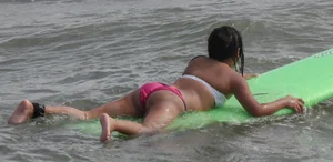 Brunette bikini girl on the beach and surfing in her bikini