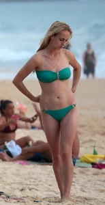 Sexy brunette in thong bikini and blonde friend in green bikini at the beach