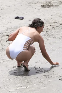 Sexy brunette babe on the beach in a white swimsuit
