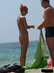 Topless skinny blonde lady in a g-string bikini at the beach