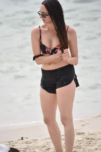 Brunette girl in black shorts and bikini top on the beach
