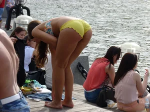 Cute Girl in Denim Shorts and Swimsuit Undressing on the Riverbank Candid Photo