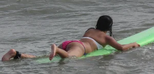 Brunette bikini girl on the beach and surfing in her bikini