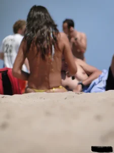 Topless lady on the beach in a gold thong with a nice ass