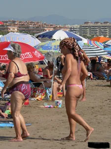 Topless tattooed lady at the beach with a nice ass in pink thong bikini