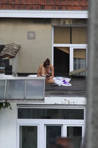 Neighbor on rooftop tanning in bikinis