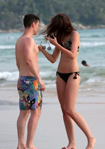 Babe in black bikini on the beach with her boyfriend
