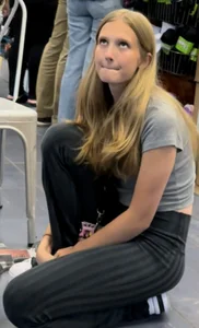 Cute girl in tight pants standing on one knee on the floor, very long legs