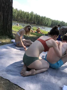 Pale Girl in Swimsuit Standing on Her Knees at a Lake Beach Creepshot