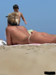 Hot blonde on the beach topless and in a white thong bikini