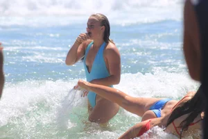 Blonde in blue thong swimsuit on the beach with friends