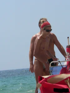 Topless skinny blonde lady in a g-string bikini at the beach