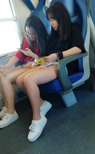 Two cute Asian teens on the bus in shorts showing their legs