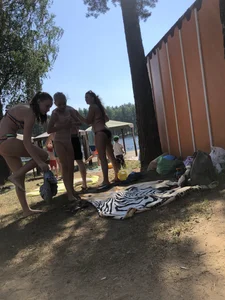 Young Skinny Girl Taking Off Her Denim Shorts Leaving a Swimsuit - Bending Over While Laying a Blanket on the Ground at a Lake Nature Park Gallery