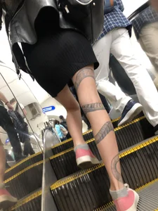Girl in a Skirt With a Snake Tattoo on Her Leg Standing With Spread Legs on an Escalator Creepshots Series